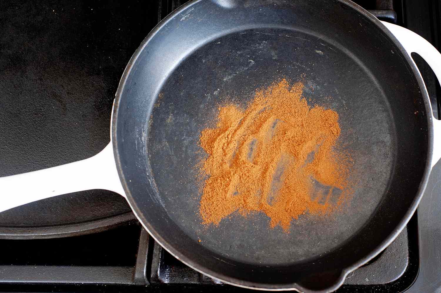 Toasting cinnamon in a skillet to make cinnamon ice cream.