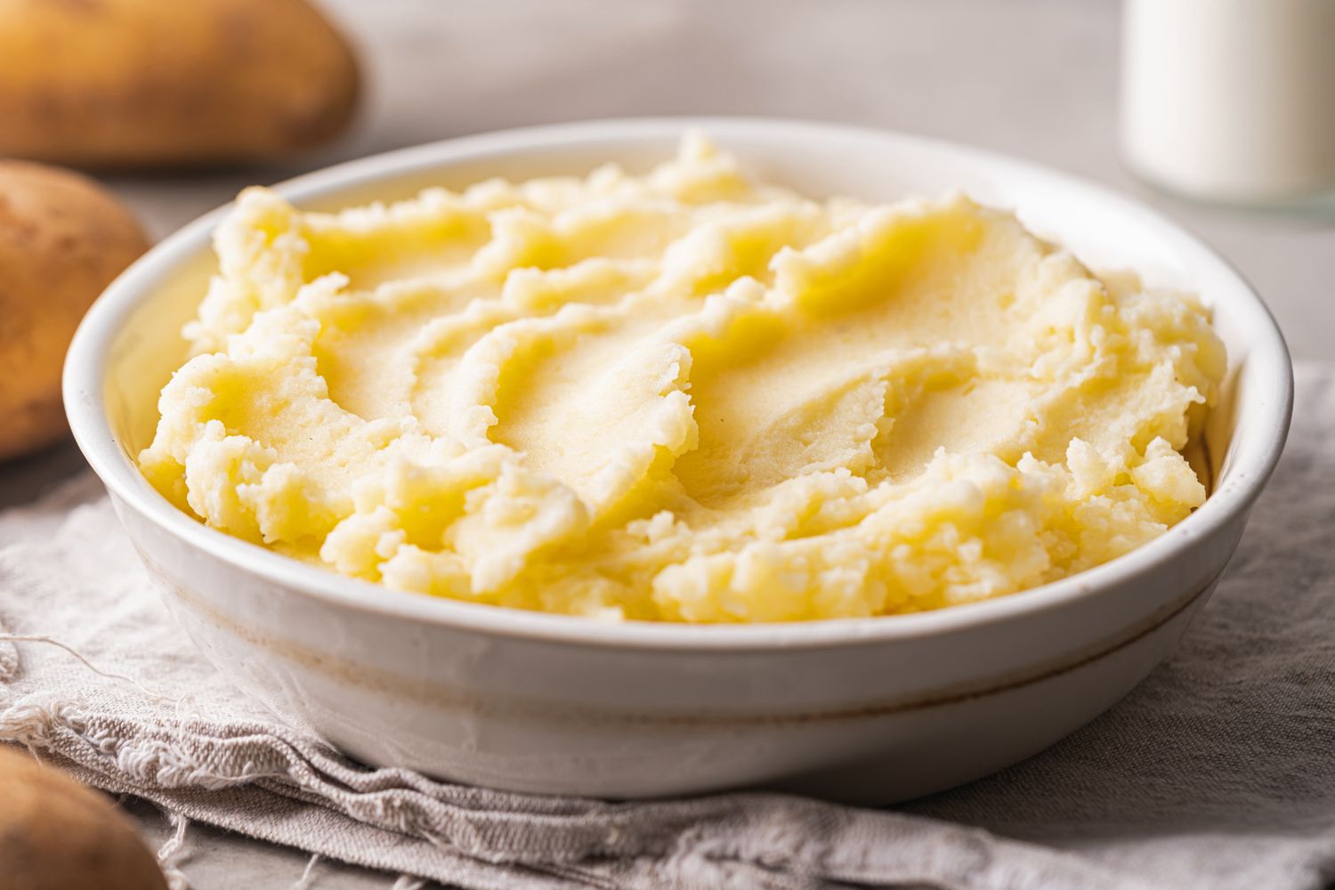 A bowl of mashed potatoes on a cloth napkin rustic appearance and soft textured top