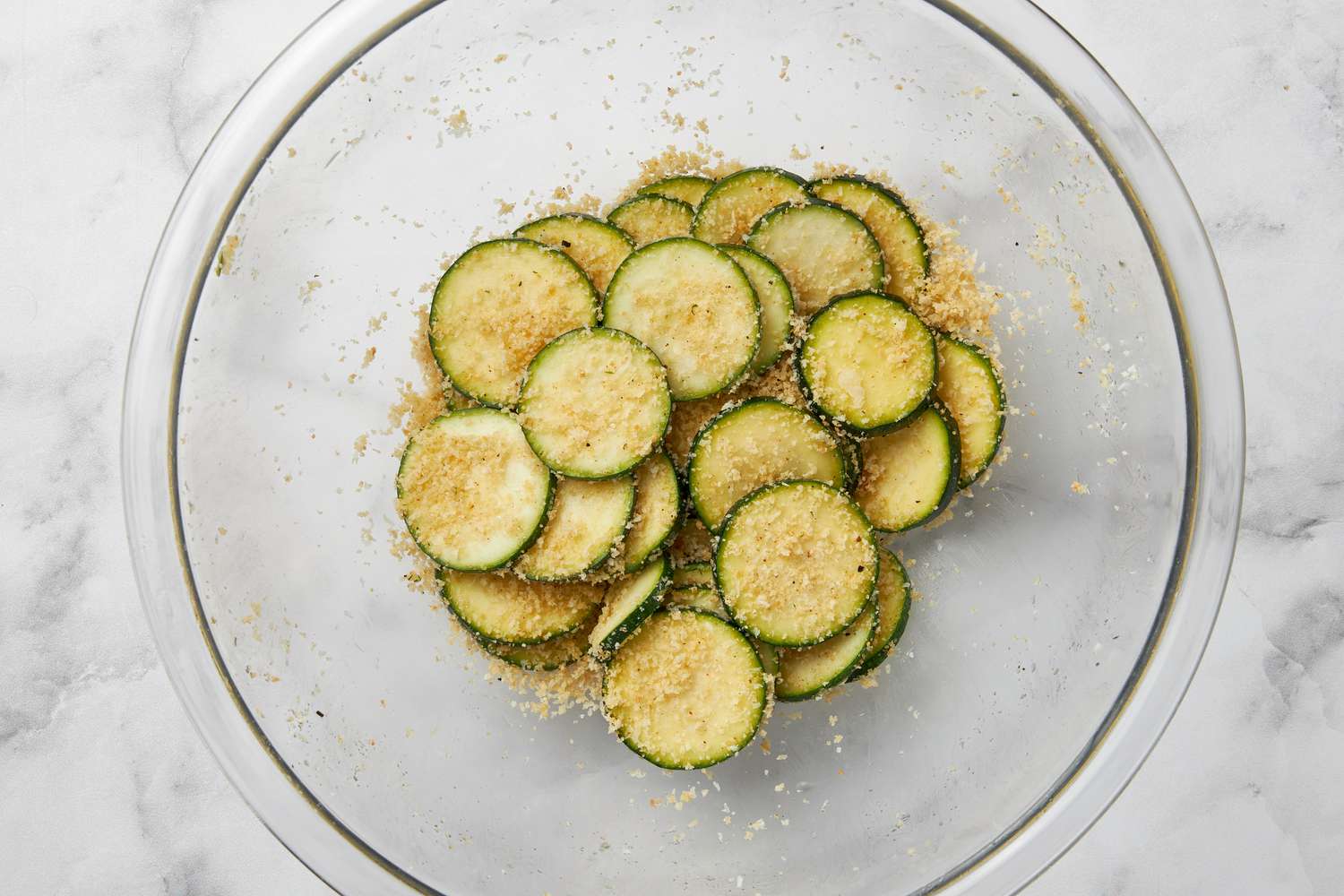 Zucchini slices tossed with the breading in a bowl