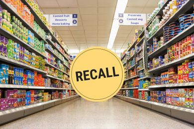 Supermarket aisle with canned goods a large yellow recall sign in the center