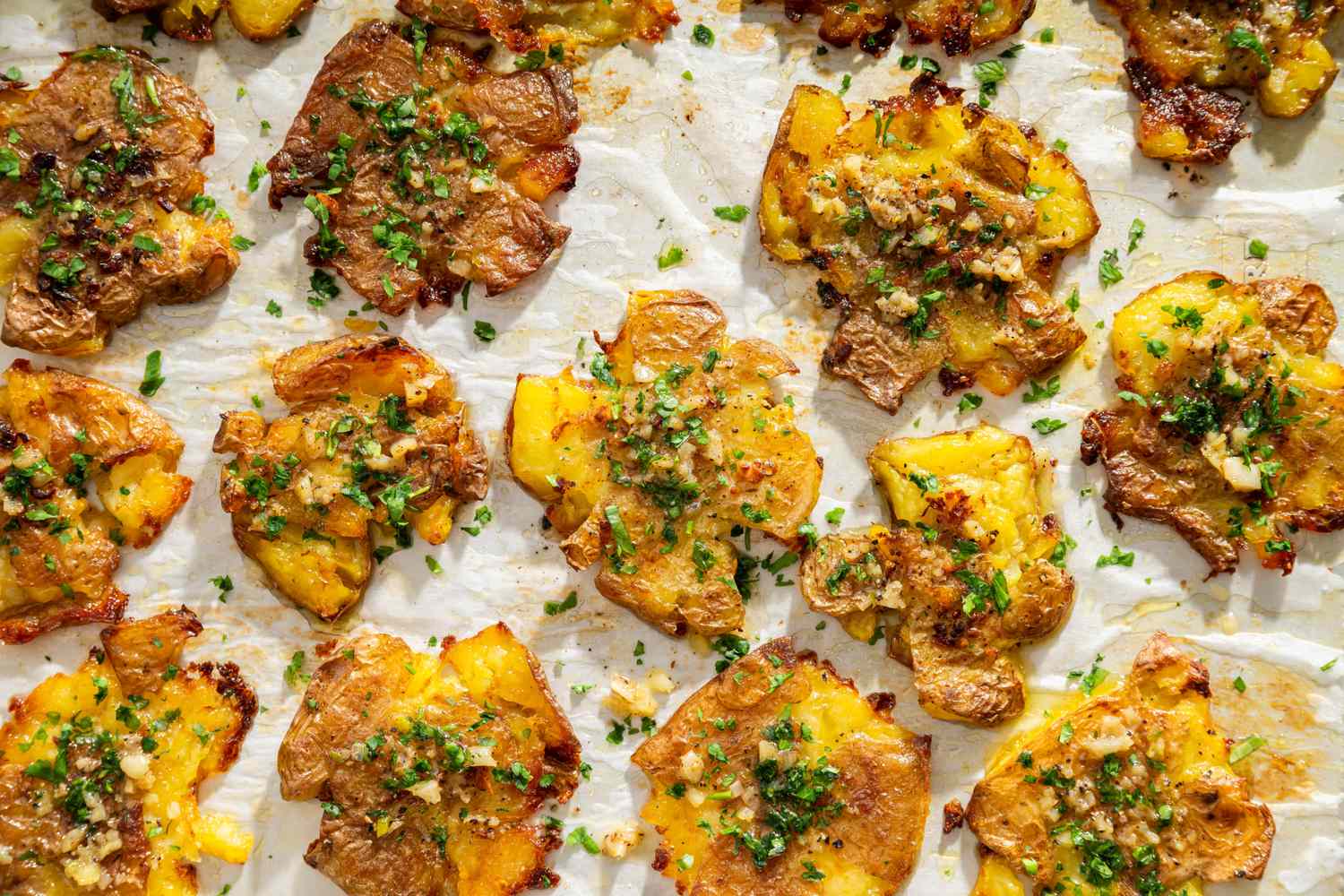 Garlic butter smashed potatoes garnished with herbs on a baking sheet