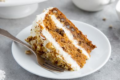 Closeup shot of a slice of layer carrot cake with cream cheese frosting on a plate
