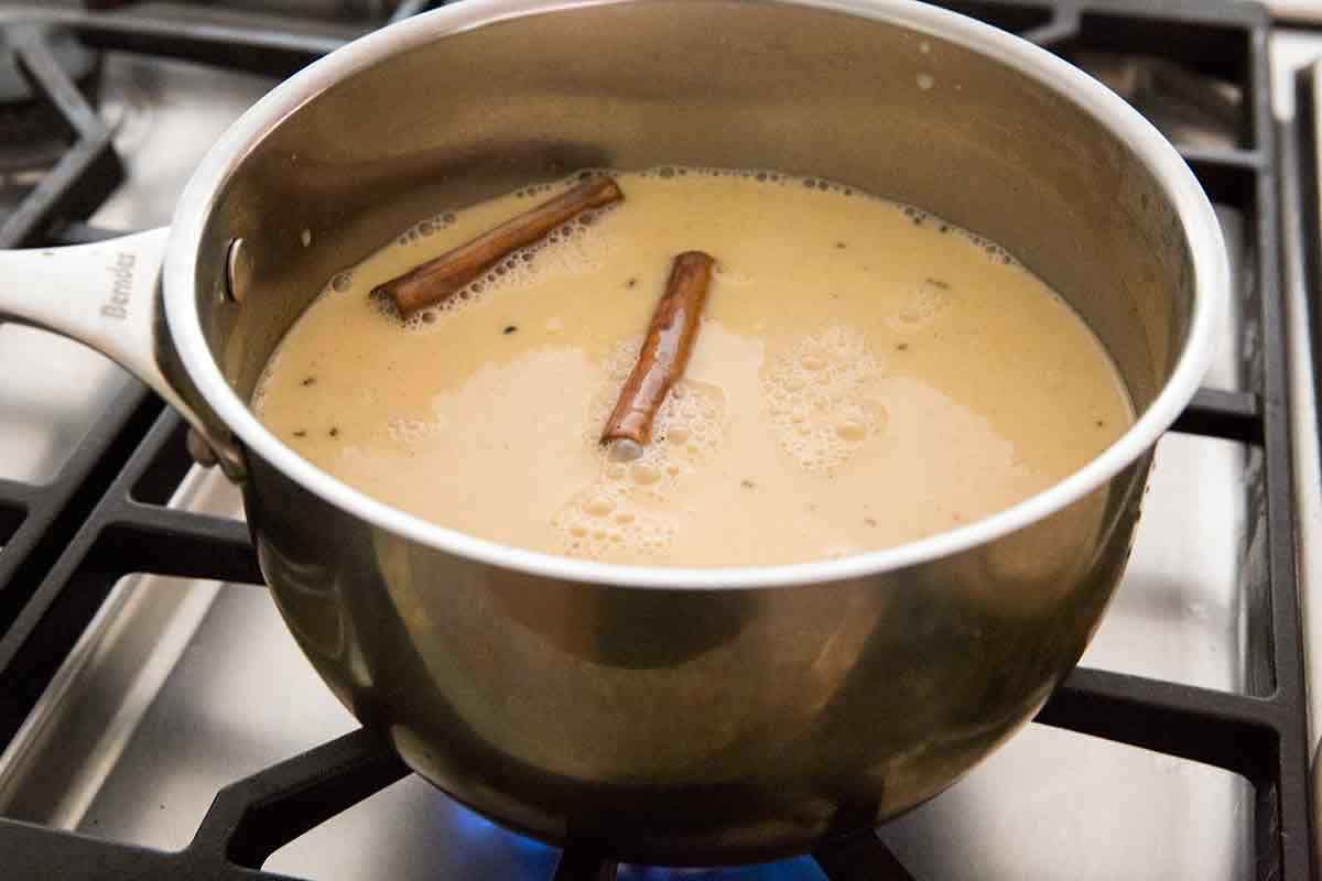 Spices steeping in milks for Coquito on a gas stove