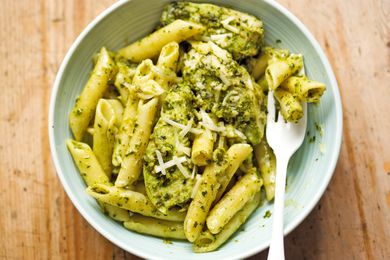 Penne pasta served with pesto garnished with grated cheese