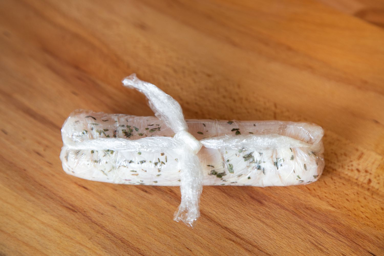 Chicken wrapped in plastic wrap to make a poached chicken recipe.