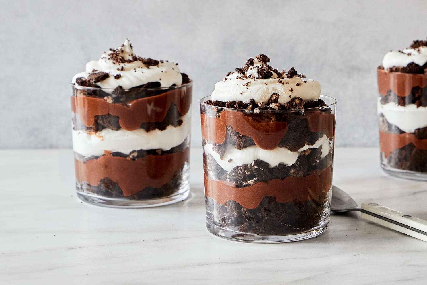 Layered dessert cups with chocolate whipped cream and cookie crumbles