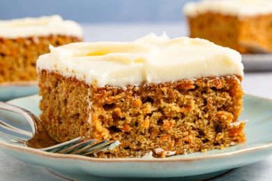 A piece of carrot cake with cream cheese frosting on a plate with a fork