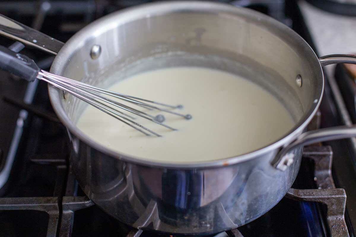 Milk is brought to a simmer in a saucepan on the stove to make Easy Cauliflower Bake.