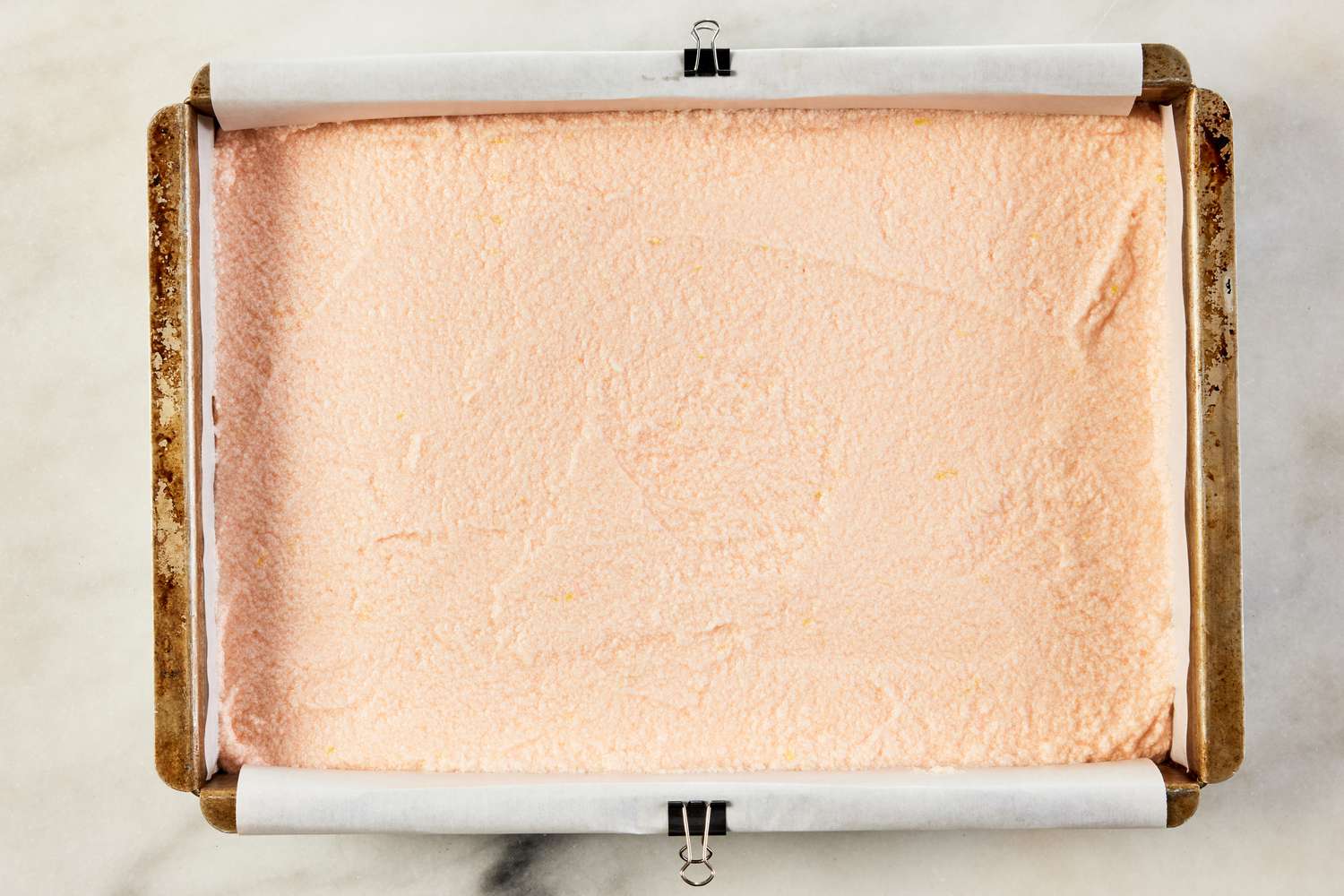 pink lemonade cake batter added to a baking pan 