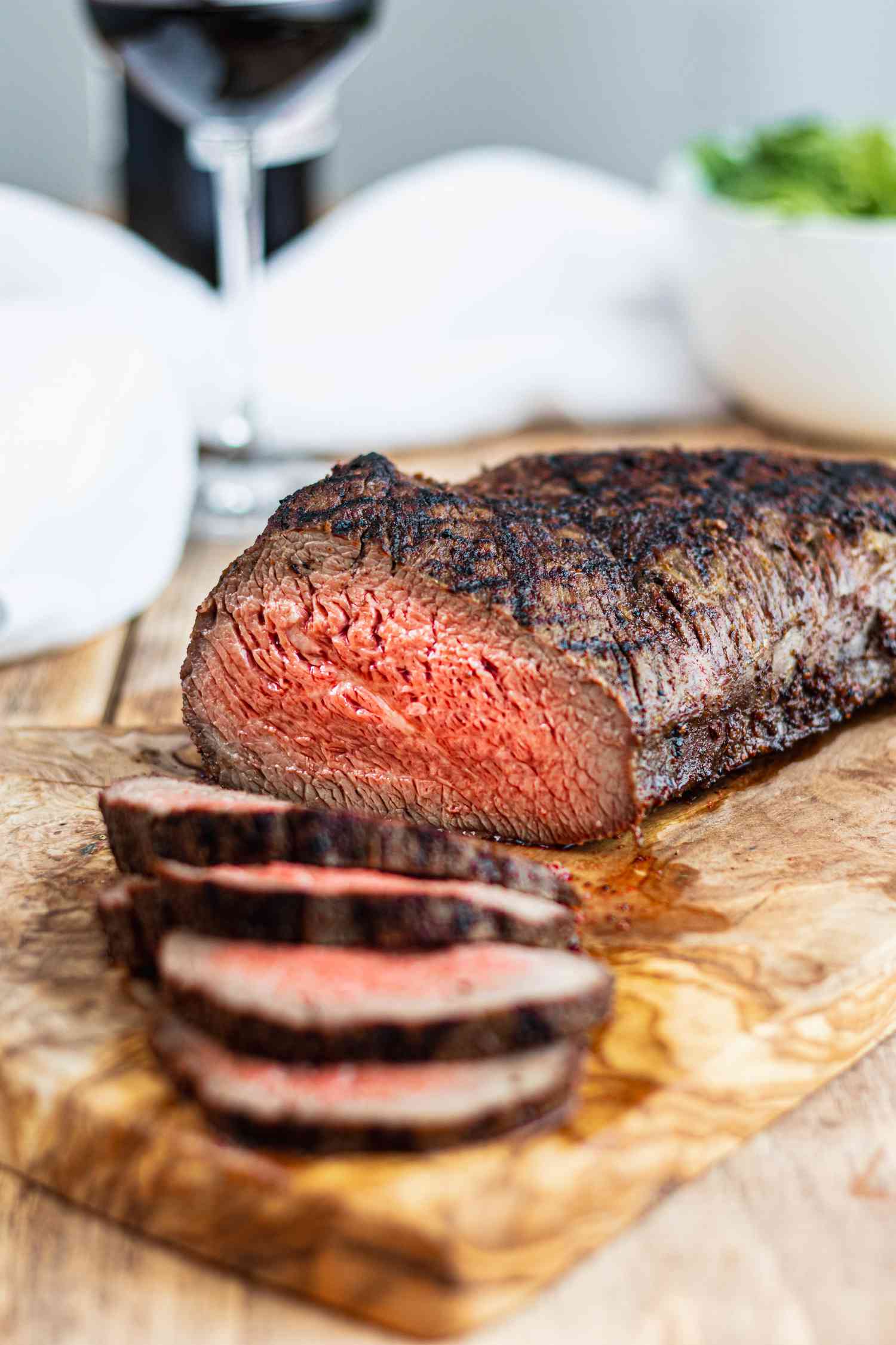 A cutting board with slices of tri tip steak laid in front of the remaining roast.
