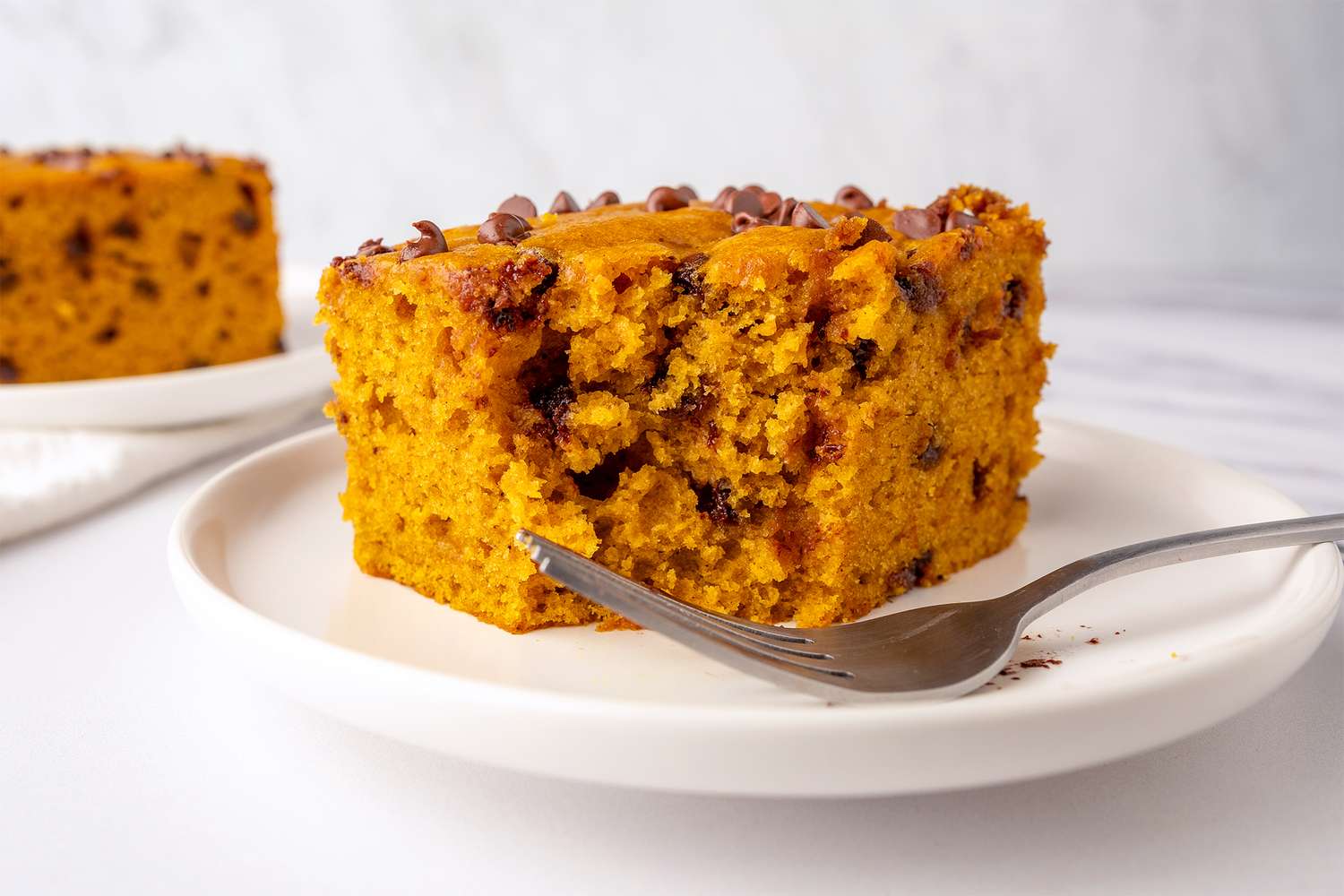 Slice of pumpkin chocolate chip cake on a plate with a fork