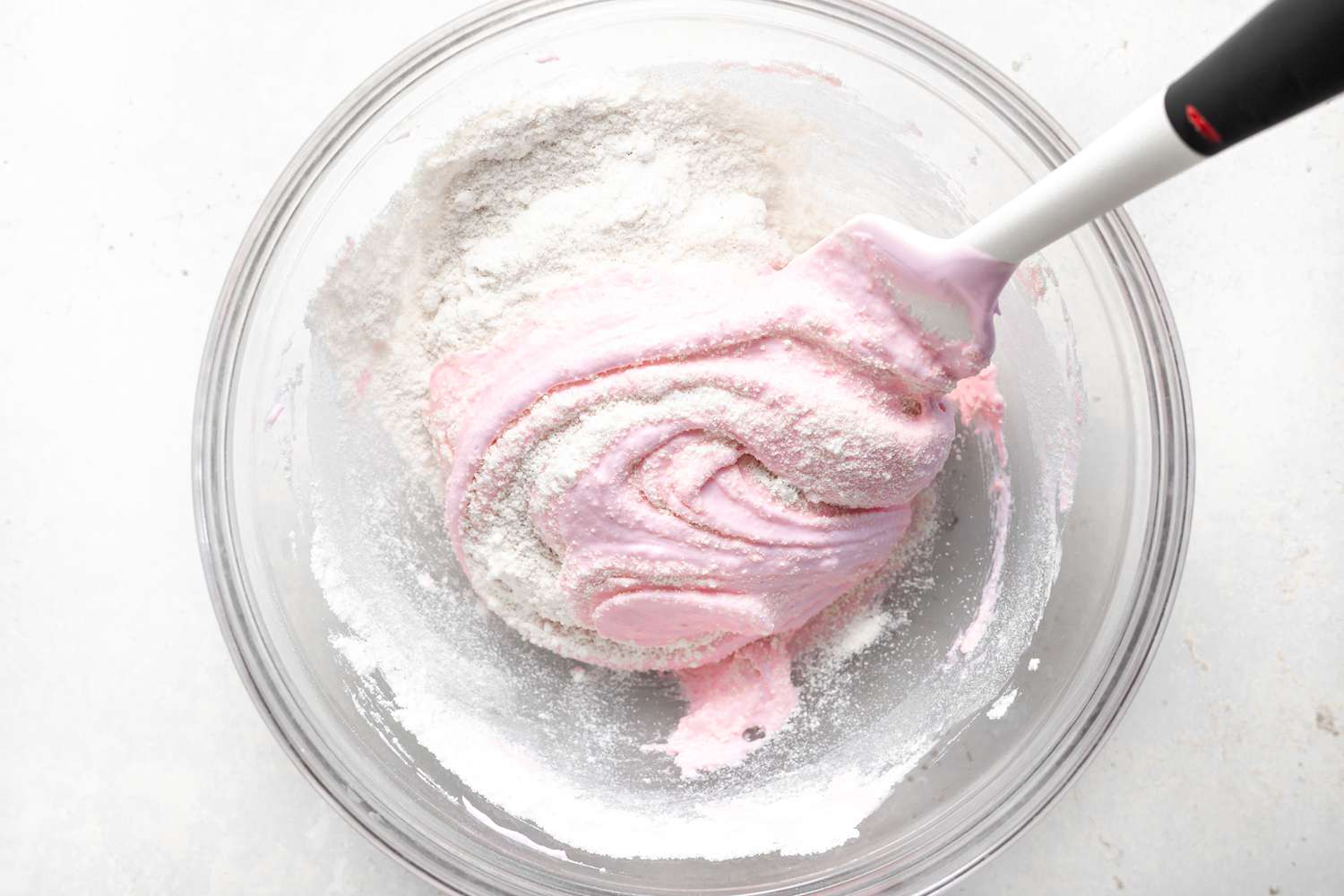 Mixing in dry ingredients to make strawberry macarons.