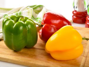 Red, green and yellow peppers on a cutting board
