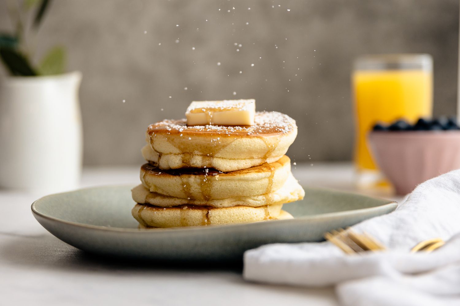 Japanese Souffle Pancakes Topped with Butter, Maple Syrup, and Powdered Sugar on a Plate