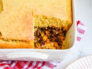 A casserole dish with a tamale pie and a piece missing.