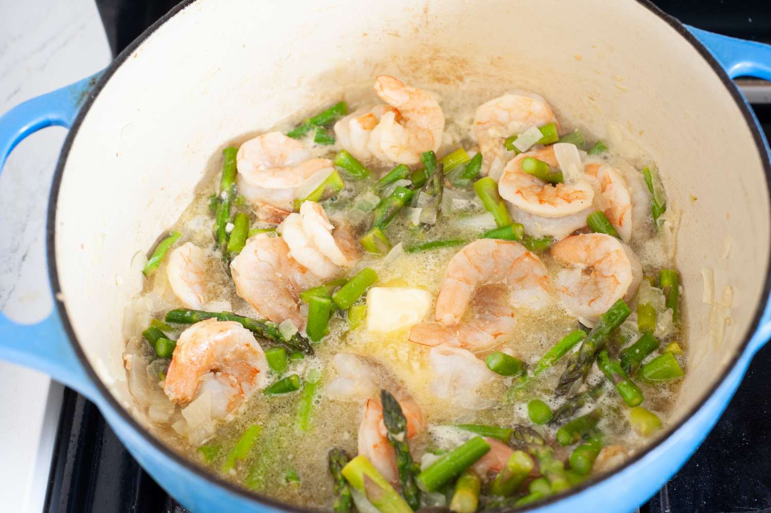 Wine and Butter Added to Shrimp and Asparagus in Dutch Oven 