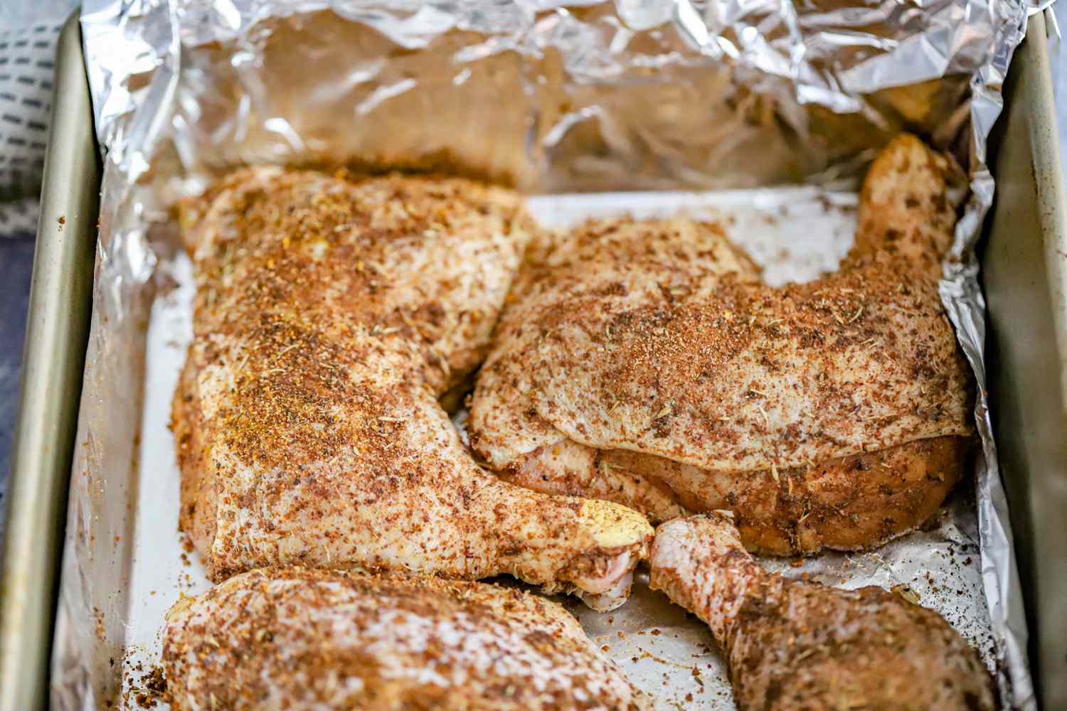 Chicken Legs Pieces Rubbed in Jerk Seasoning Laying in a Aluminum Sheet Wrapped Baking Pan