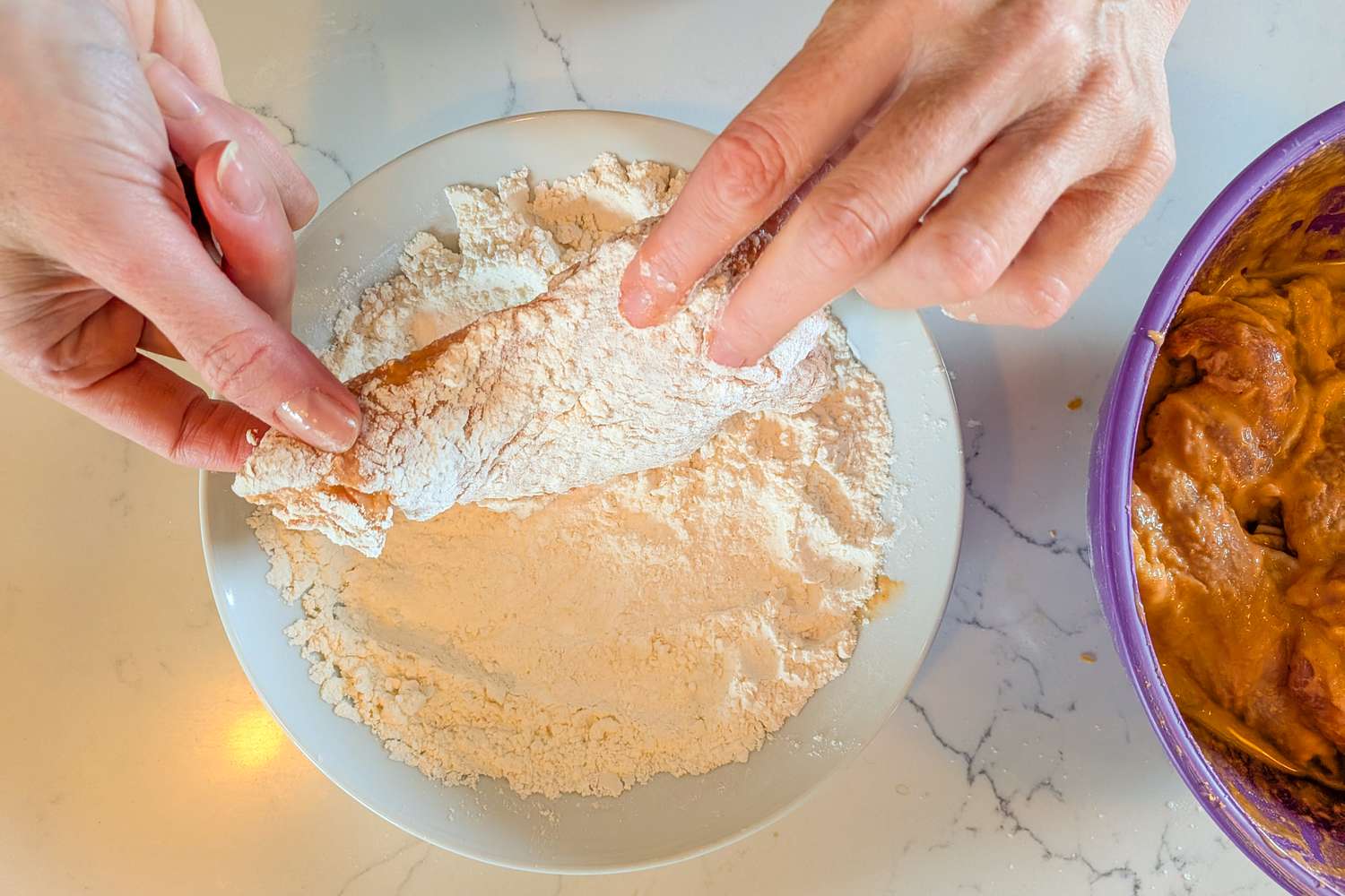 Hands breading a piece of chicken with flour a preparation step for cooking
