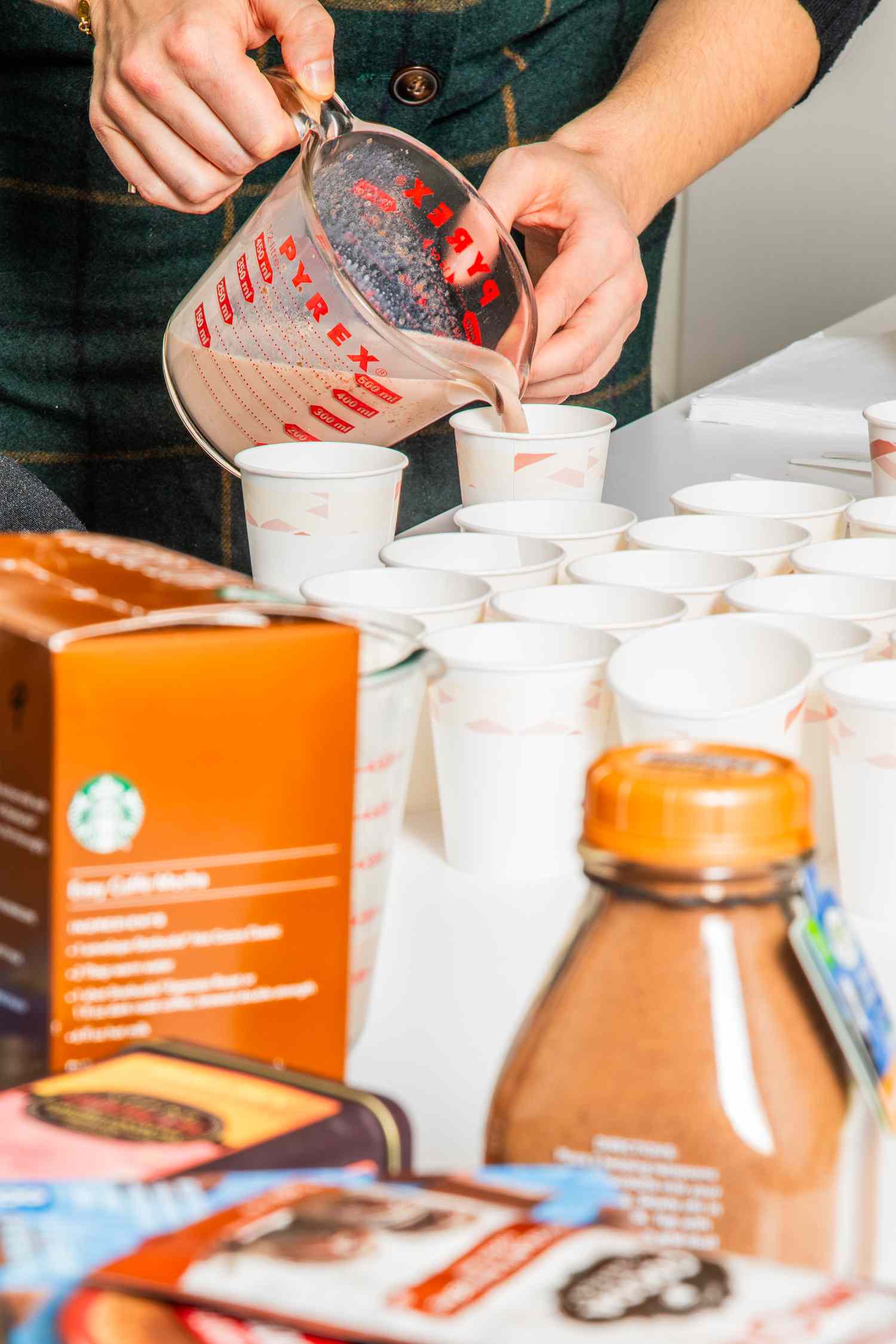 Hand pouring hot cocoa into small white cups