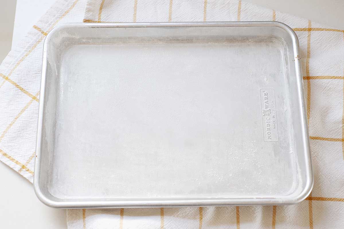 An empty baking sheet on a striped linen.