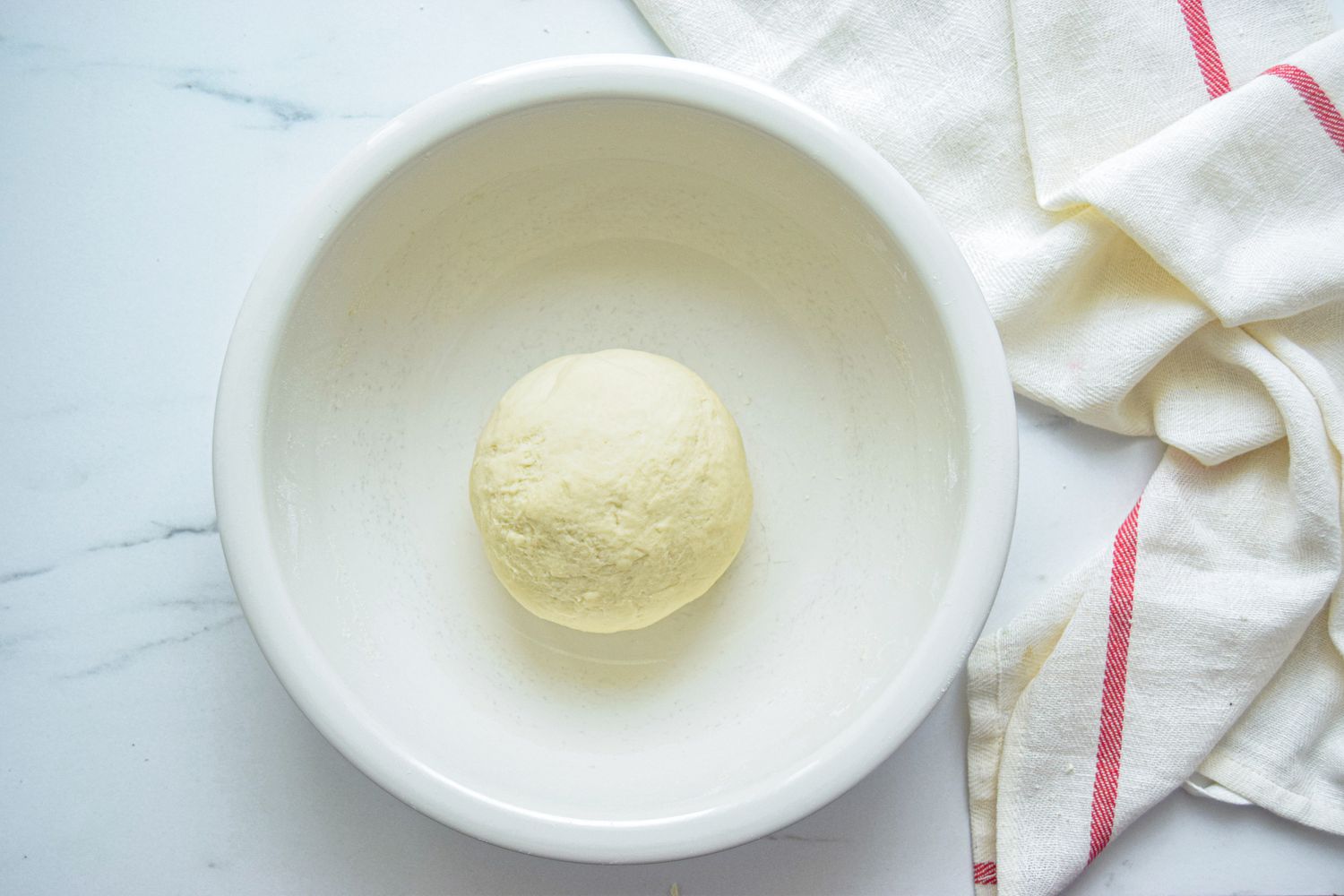 Dough in a white bowl to make homemade scallion pancakes.