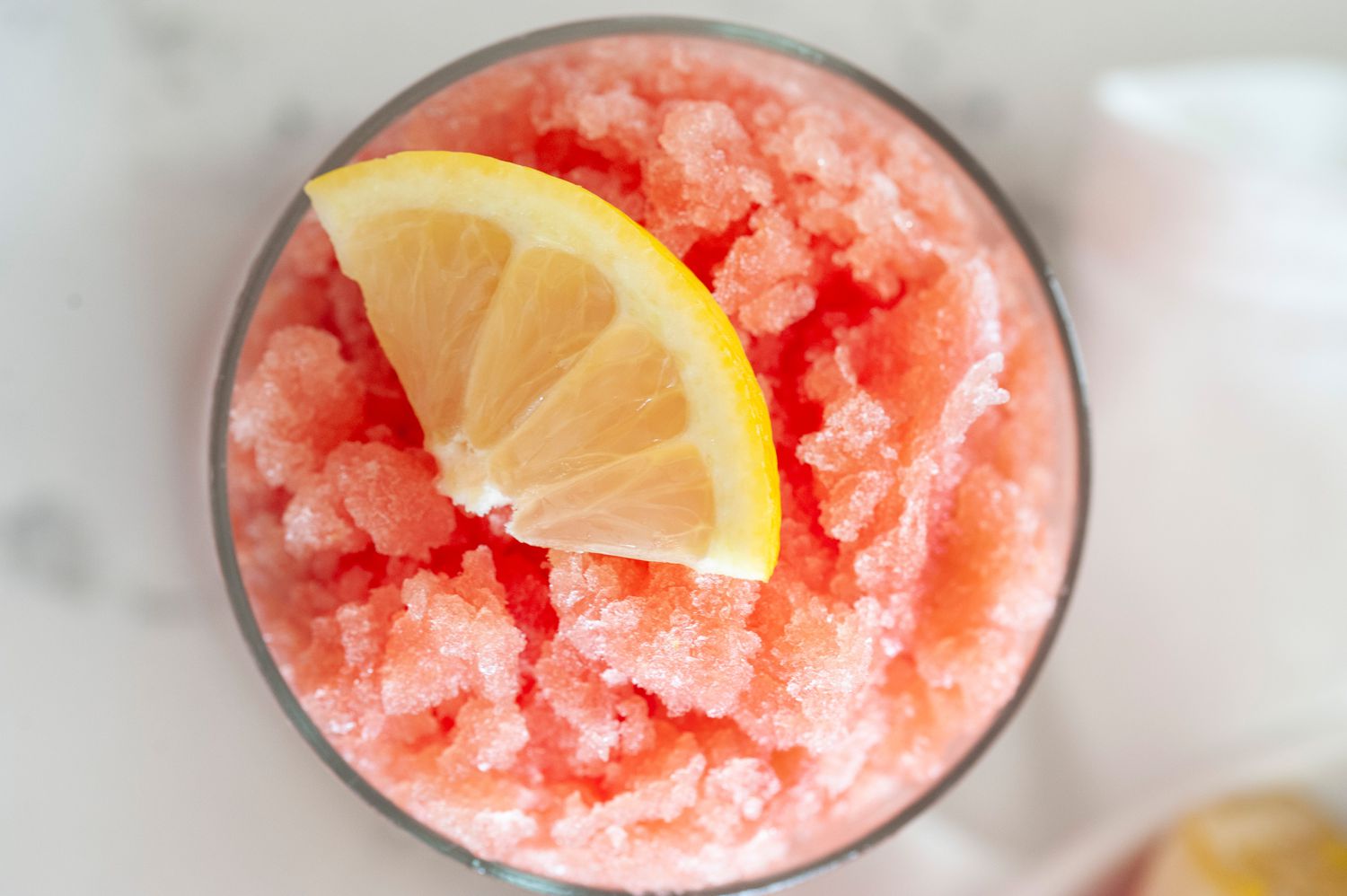 Top view of a watermelon granita toped with a lemon slice.