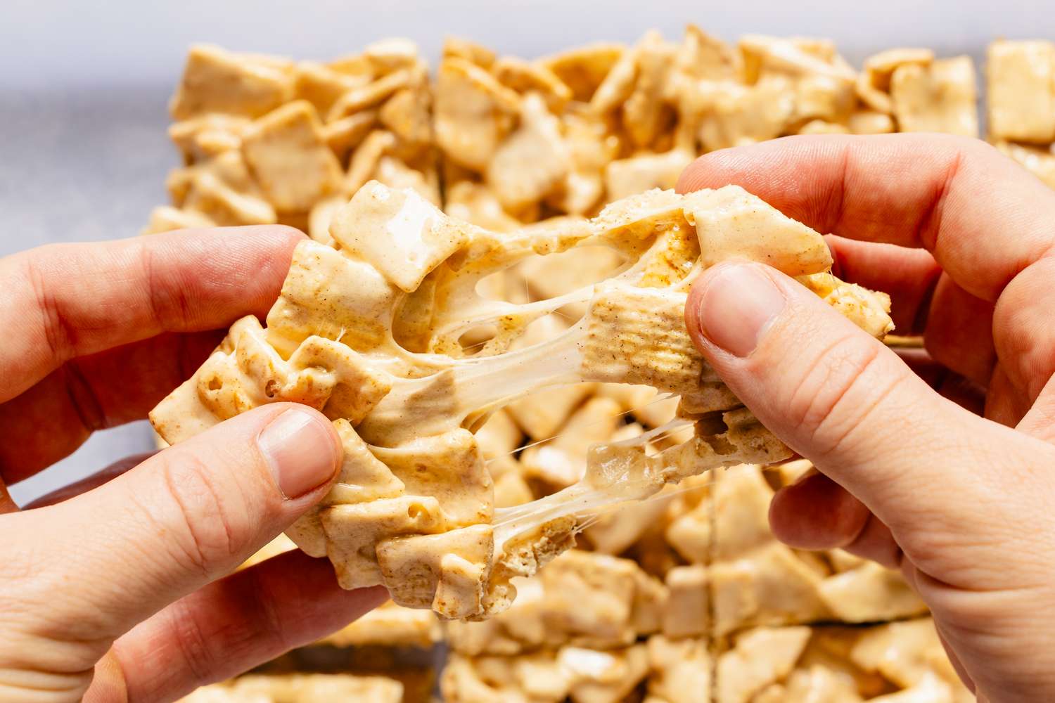 Two hands pulling apart a gooey Cinnamon Toast Crunch bar