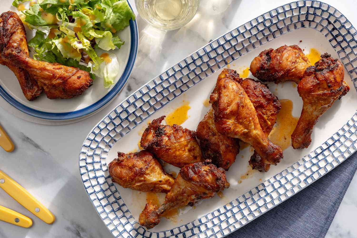 overhead view of Spiced Chicken Drumsticks on a platter and a plate with salad on the side of drumsticks