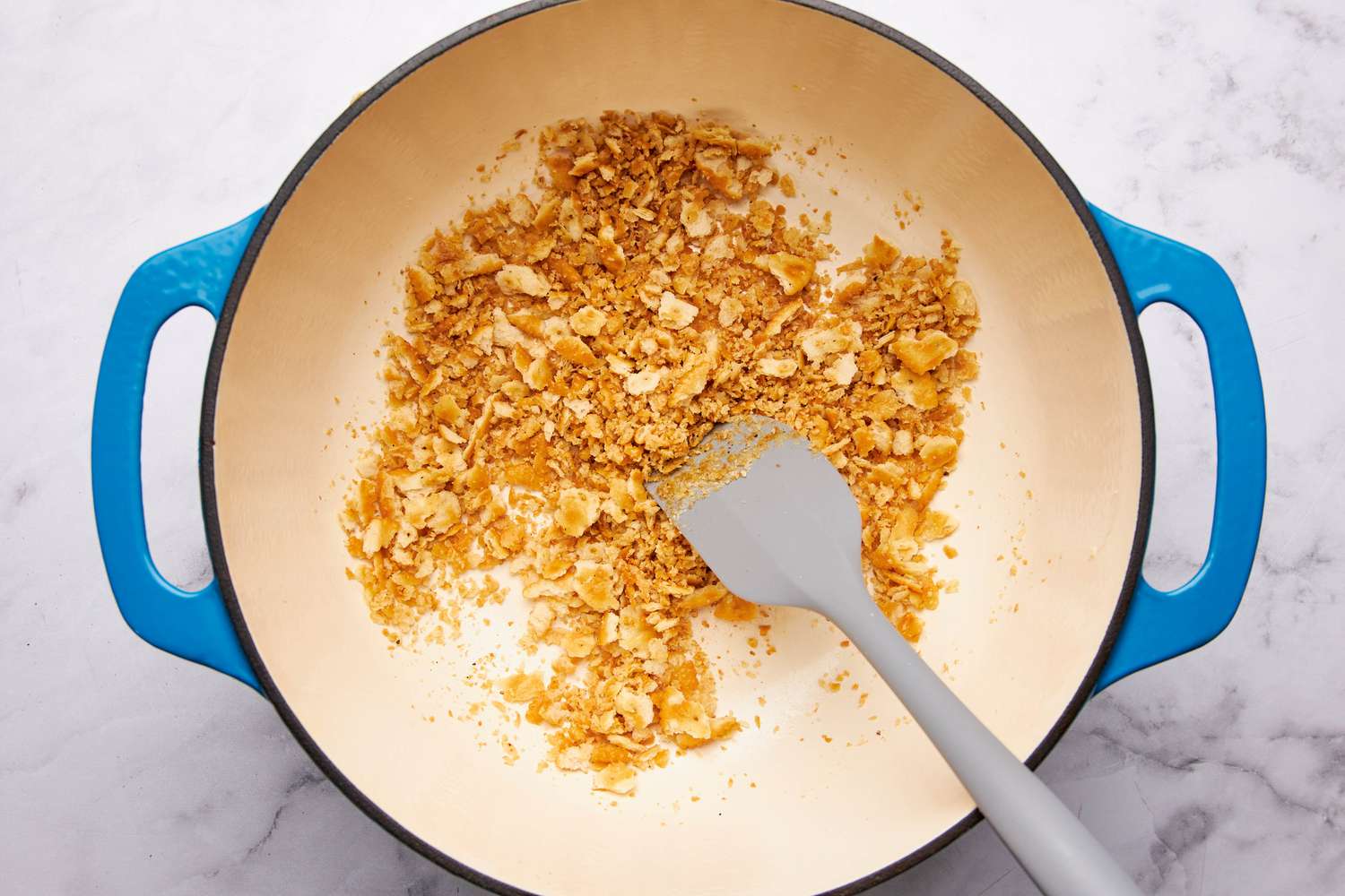 Ritz cracker topping toasting in the dutch oven and mixed using a rubber spatula
