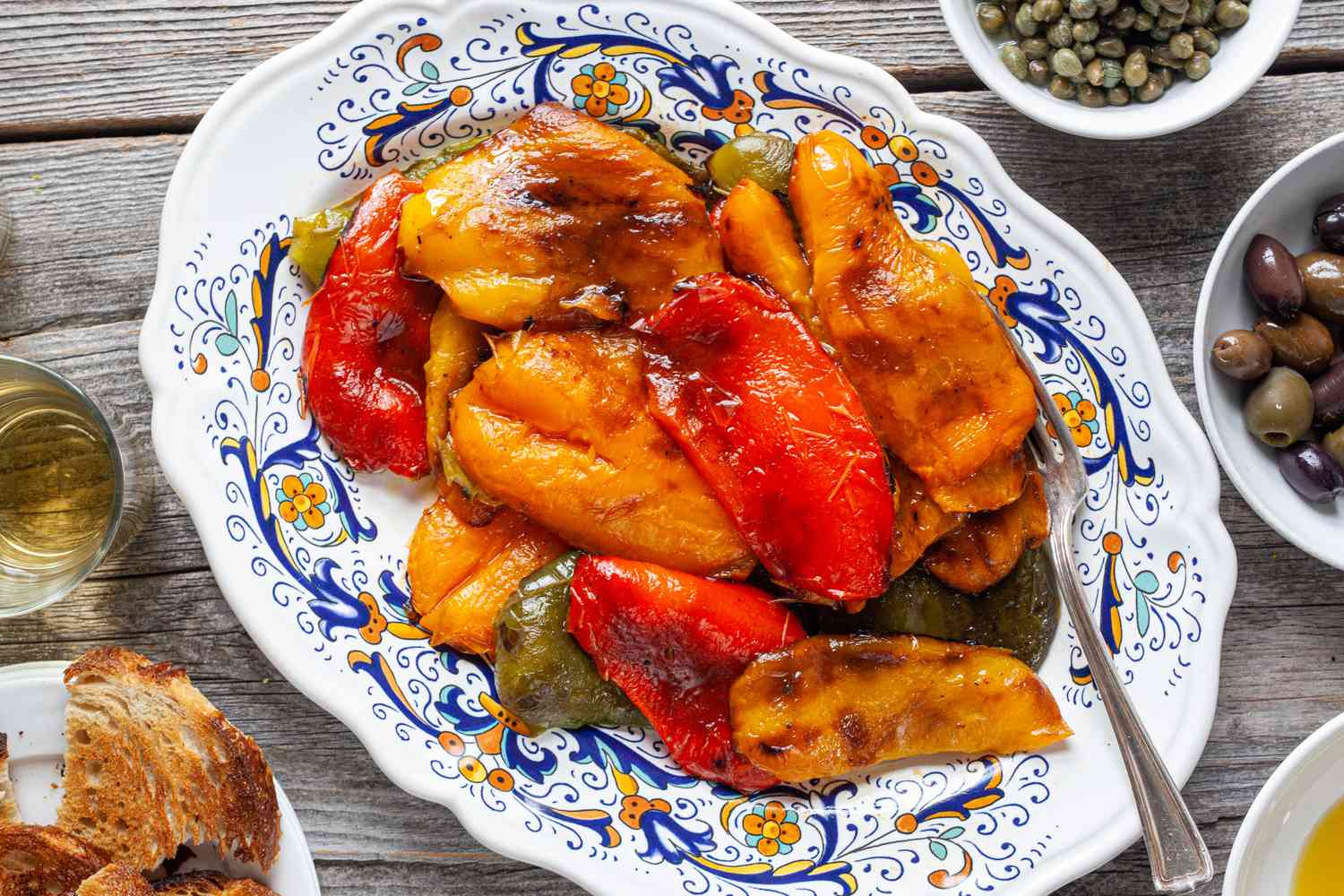 Platter of Grilled Peppers Surrounded by Olives, Capers, Olive Oil, and Toast