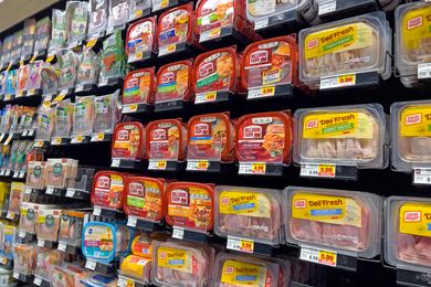 Shelves stocked with various packages of delisliced turkey from different brands in a grocery store