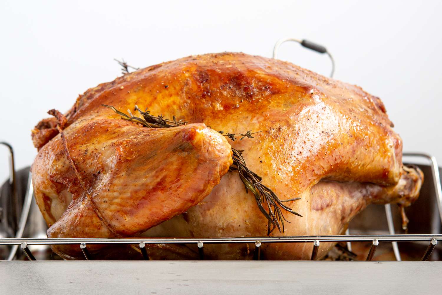 A roast turkey breast-side-down on a roasting rack in a roasting pan