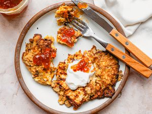 Overhead view of a plate of Matzo Brei Pancakes with a fork and knife on a pink marble countertop