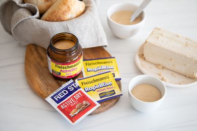 Overhead view of different types of yeast and a bowl with bread behind them.