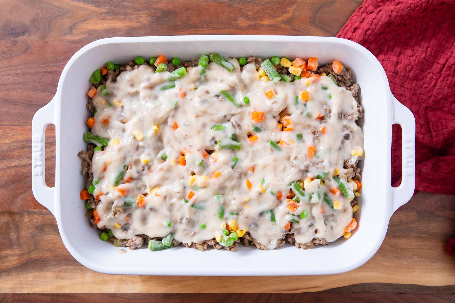ground beef, vegetables, and soup layered in a baking dish for Classic Tater Tot Hotdish