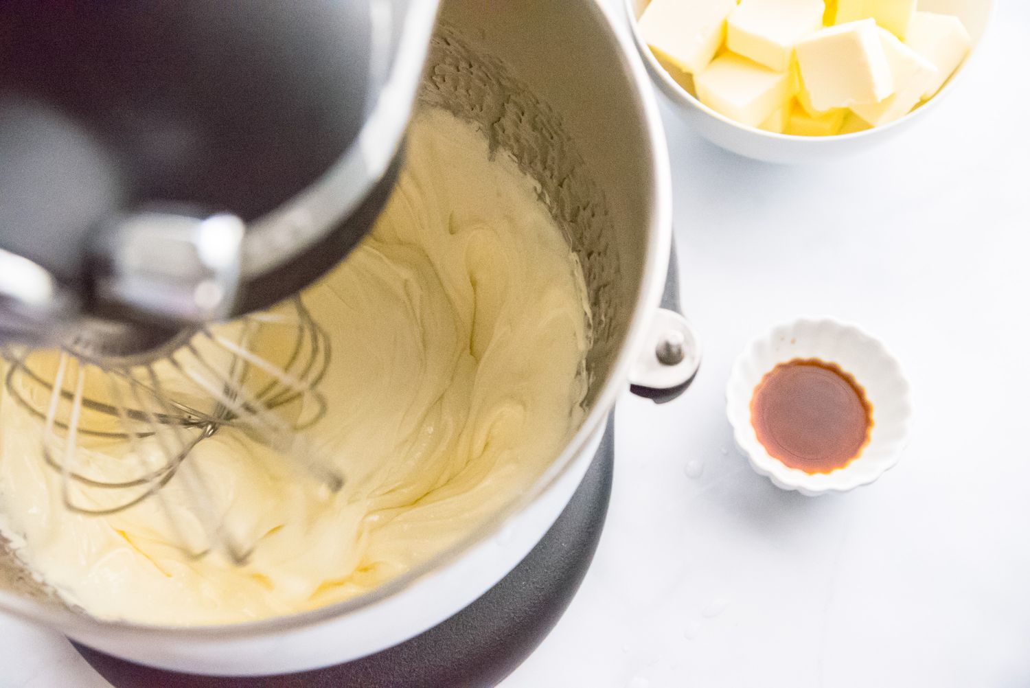 Whisking egg yolks and sugar syrup to make a French buttercream frosting recipe.