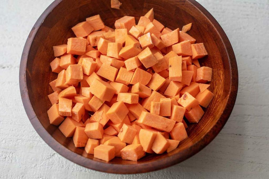 Chopped sweet potatoes in wooden bowl for cider-braised chicken thighs