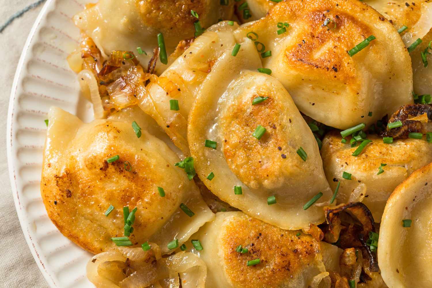 Plate of cooked pierogies topped with chopped chives