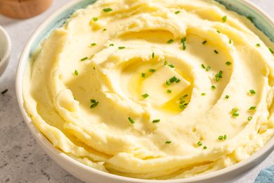 Bowl of mashed potatoes topped with butter and chives