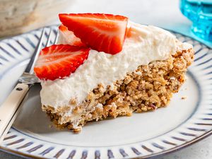 soda cracker pie slice (topped with whipped cream and fresh strawberries) on a small plate with a fork