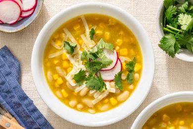 Bowl of chili verde topped with radishes cheese and cilantro