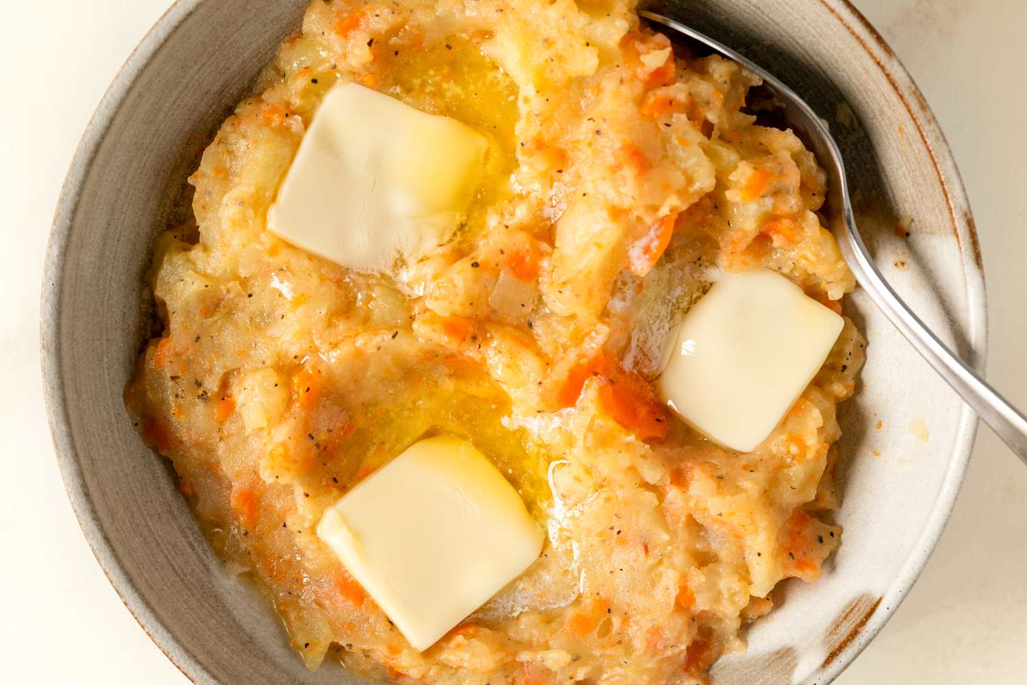 Served bowl of mashed vegetables with melting butter and a spoon