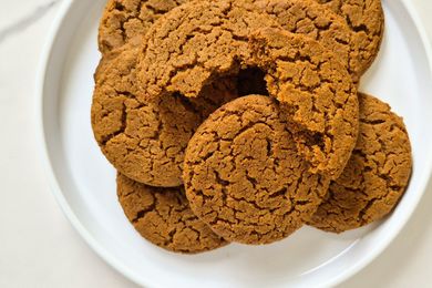 Round ginger cookies arranged on a white plate one cookie slightly broken near the center