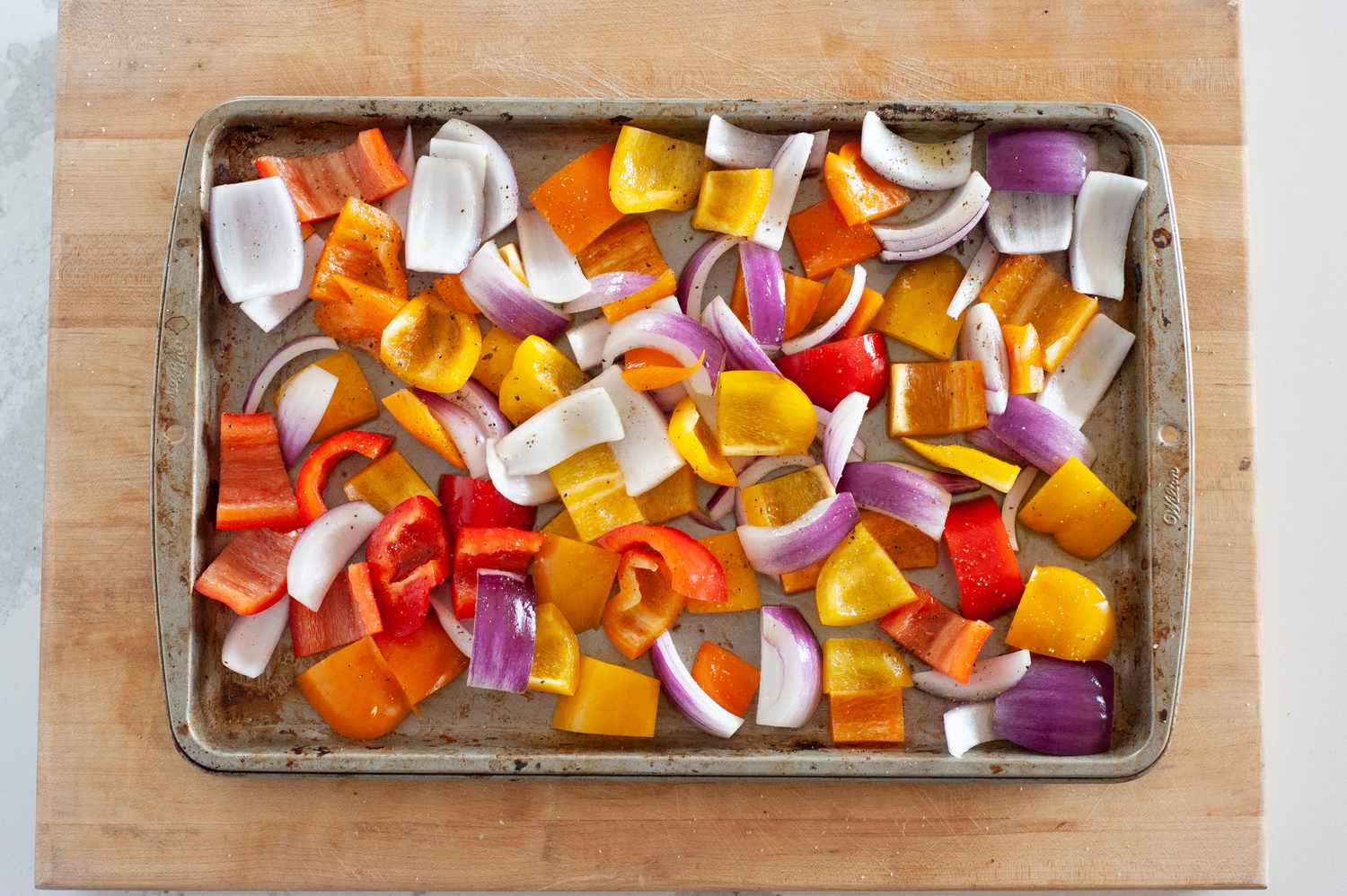 Overhead view of chopped vegetables on a cutting board to make sheet pan sausage with peppers and onions