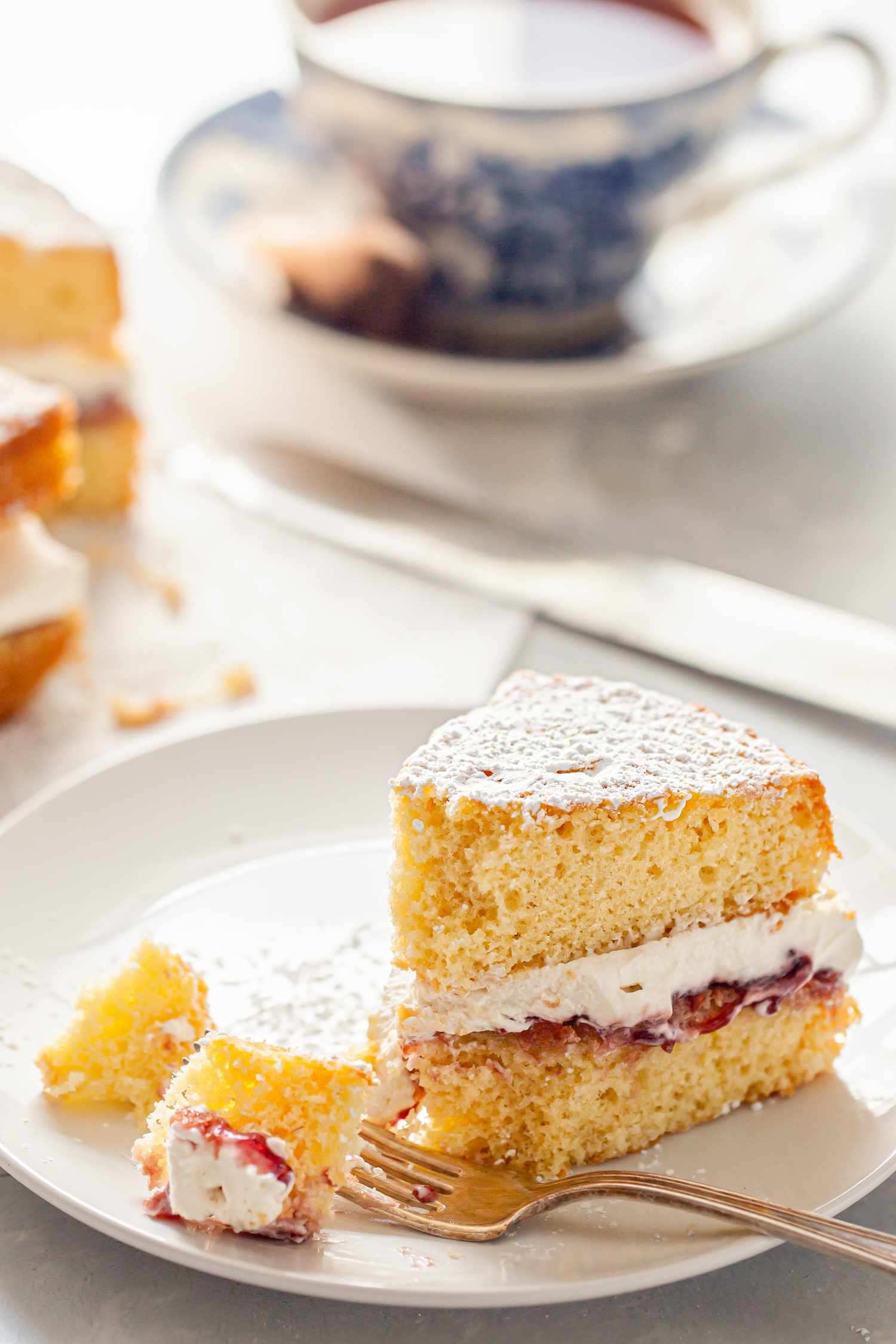 Slice of Victoria Sponge Cake on a Plate with a Forkful Removed