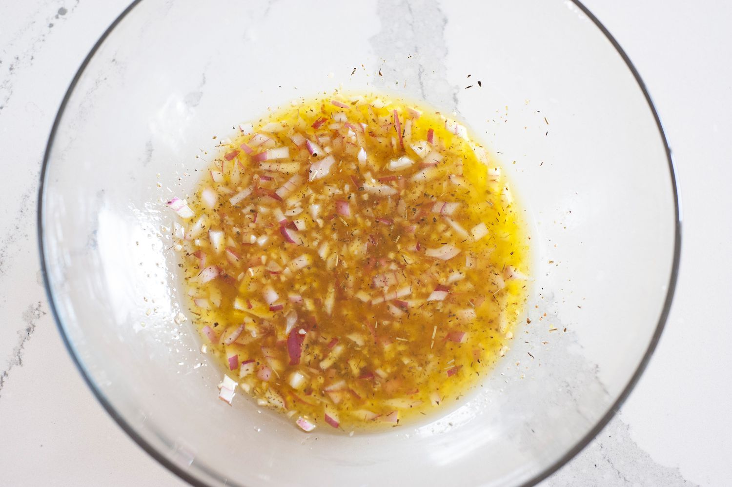 Bowl of Olive Oil Red Onions, and Seasoning for Tortellini Salad Recipe