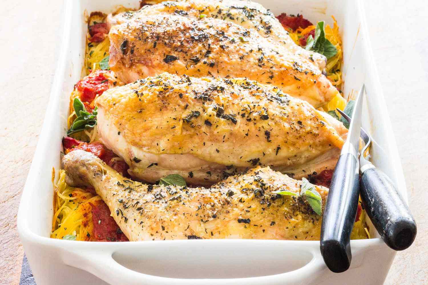 A baked chicken dish with vegetables in a white casserole dish