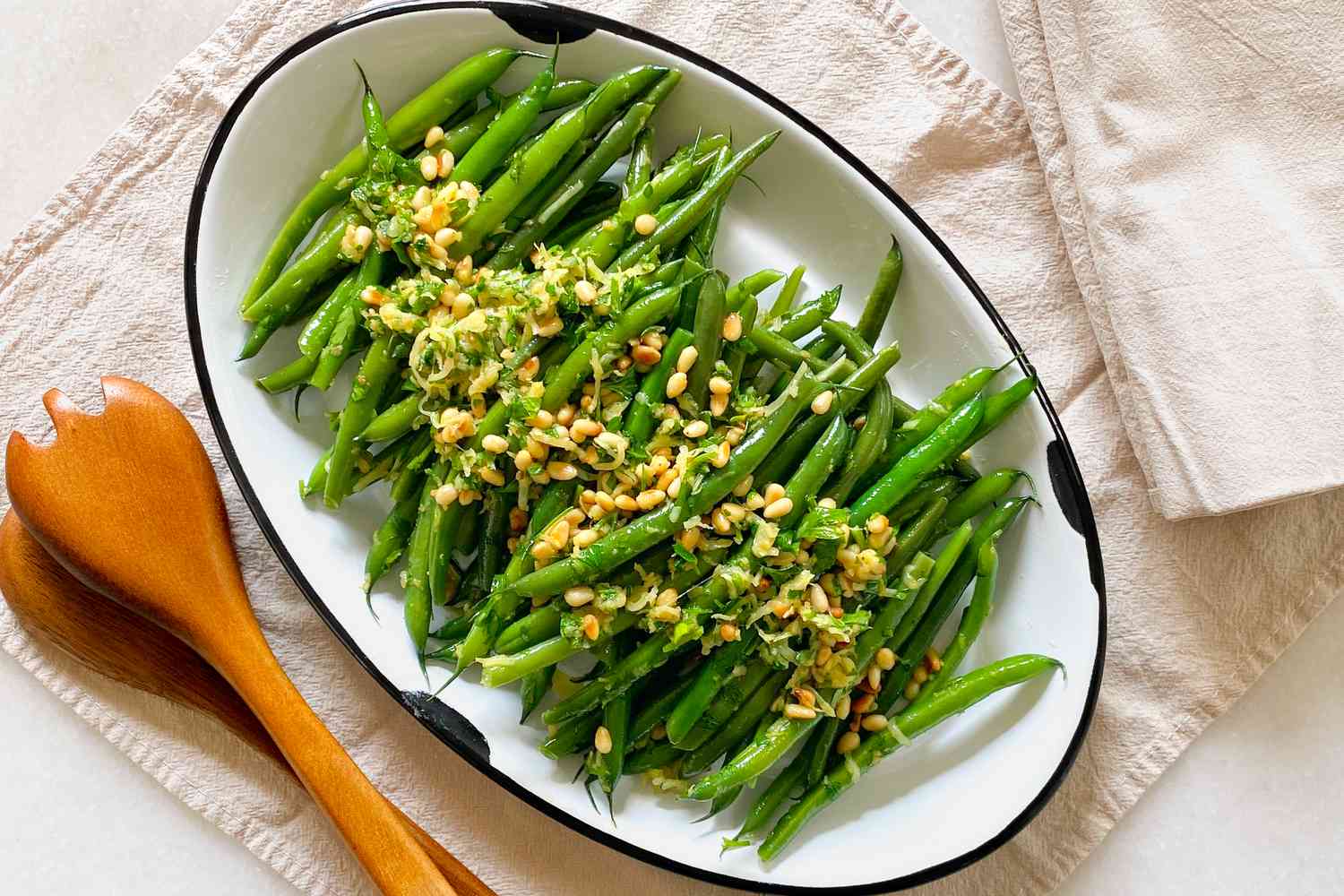 Green beans topped with lemon zest and pine nuts on a platter