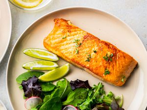 Salmon fillet on a plate with a side salad and lime slices