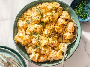 A bowl of dill pickle potato salad with a serving spoon